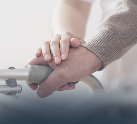 Close-up of caregiver and resident holding hands