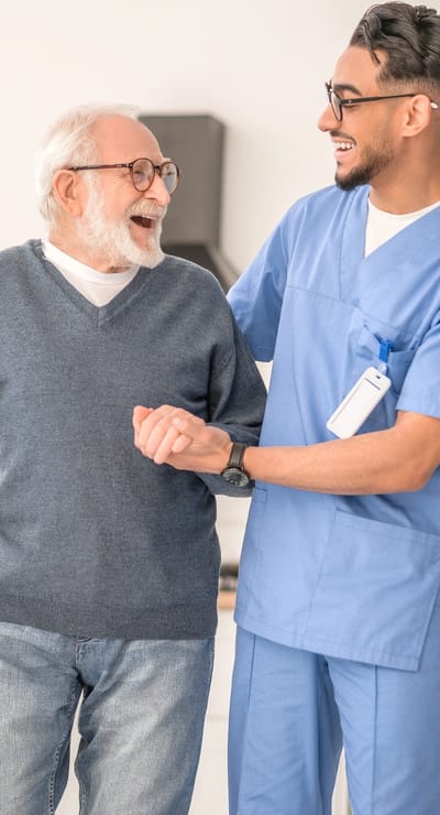 A staff member assisting a smiling resident indoors