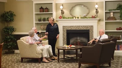 Residents interacting in a cozy common area beside a fireplace