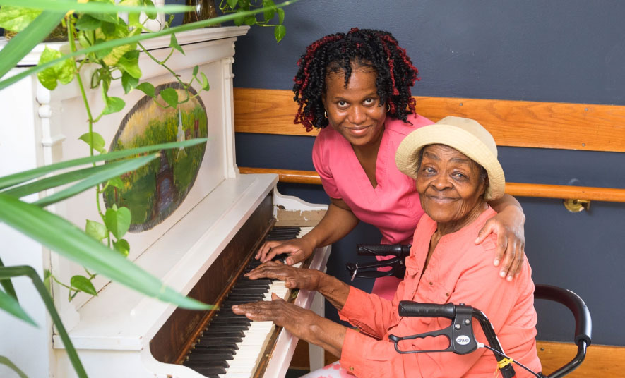 A staff member and resident playing the piano together