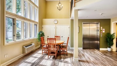Bright interior common area with dining table and elevator