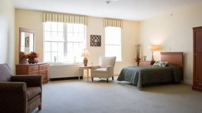 A private resident room with a bed and chair