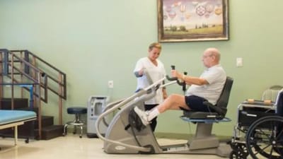 A resident using fitness equipment with staff assistance