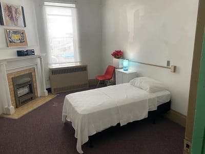 A simple resident room with a bed and chair