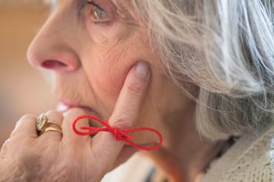 Close-up of an elderly woman with a red string.