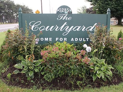 Sign for The Courtyards with surrounding flowers