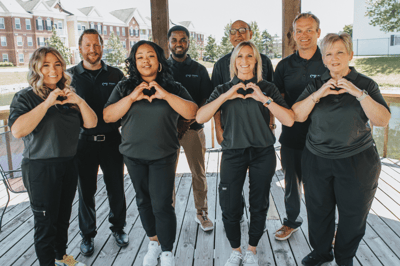 Staff members posing outdoors making heart shapes