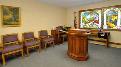Interior chapel space with wooden furniture and stained glass window