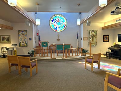 Interior view of a chapel with seating and stained glass window