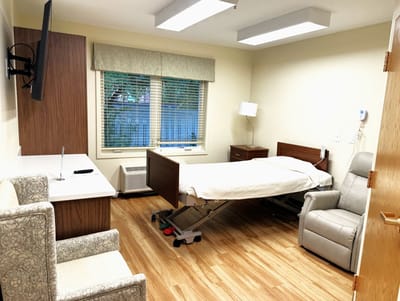 Private resident room with a hospital bed and seating