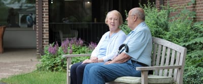 Two residents sitting on a bench in a garden