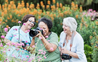 Inniswood Village National Church Residences, assisted living in Westerville, OH — Three women enjoying photography in a colorful flower garden