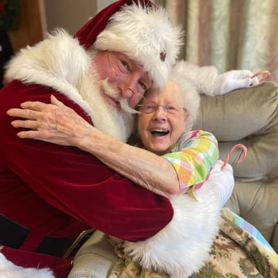 Resident joyfully hugging a Santa during holiday celebration