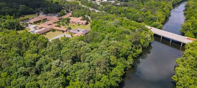 Aerial view of a senior living campus surrounded by trees and a river