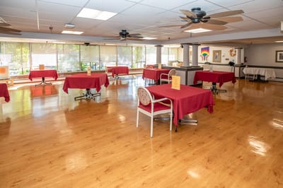 Bright common area with red tables and wooden floor