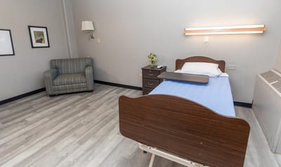 Interior of a private resident room with a bed and chair