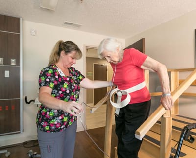 A staff member assisting an elderly woman with mobility