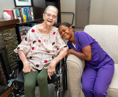 A resident and staff member smiling in a seating area