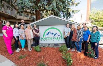 Staff and residents in front of the facility sign