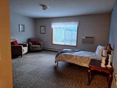 A well-furnished private resident room with a bed and seating area