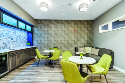 Bright common area with green chairs and tables