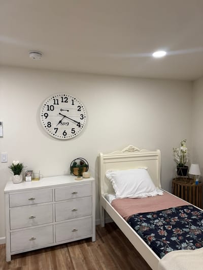 Cozy interior of a private resident room with a bed and clock