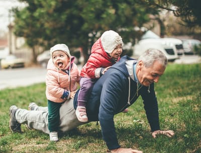 An older man playing with children outdoors