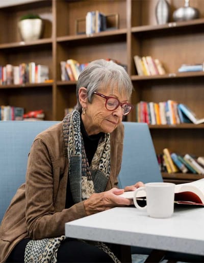 Fairway Knoll, assisted living in Germantown, WI — Senior resident reading a book in a cozy lounge