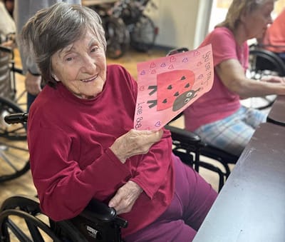 A resident smiling while showing a drawing activity.