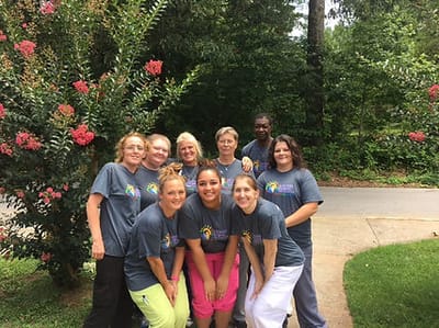 Staff members posing outside near blooming flowers