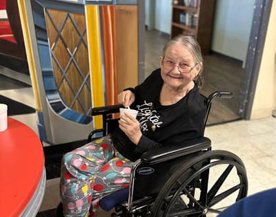 A smiling resident enjoying a treat in a common area