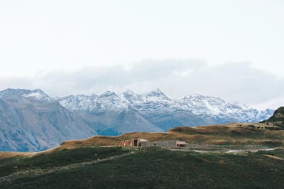 A scenic view of mountains with a small building