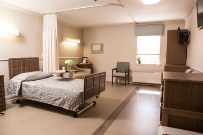 A comfortable resident room with a bed and chair