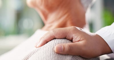 Hand on shoulder of a senior, showing care and support