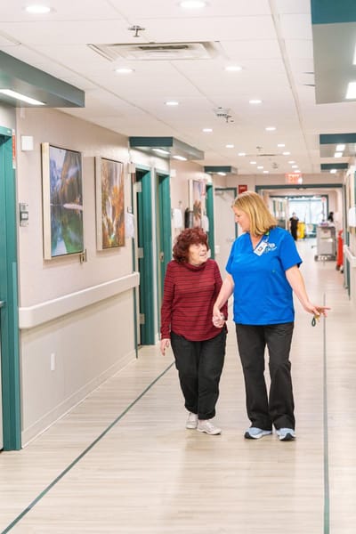 A staff member assisting a resident in a corridor