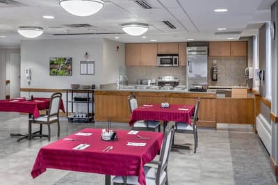 Dining area with red tablecloths and kitchen in background
