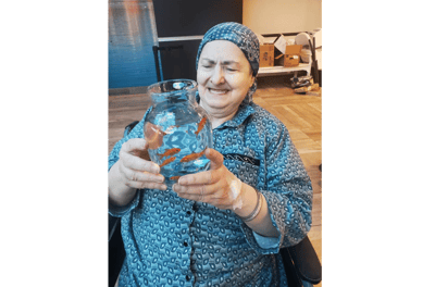 Resident joyfully interacting with a fish bowl in an indoor setting