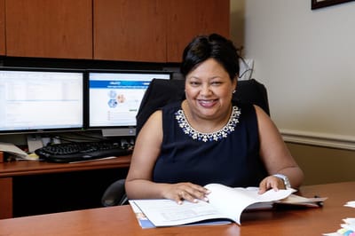 Staff member smiling while reviewing documents at a desk