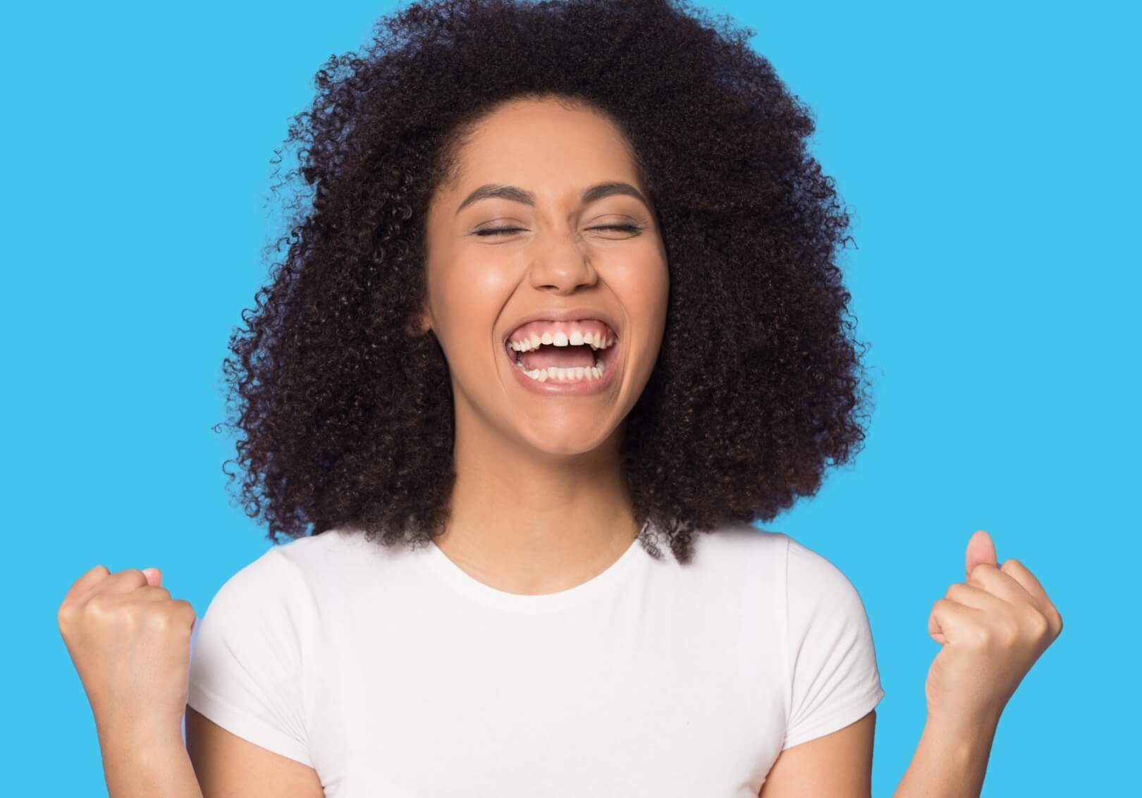 A young woman with curly hair smiling widely