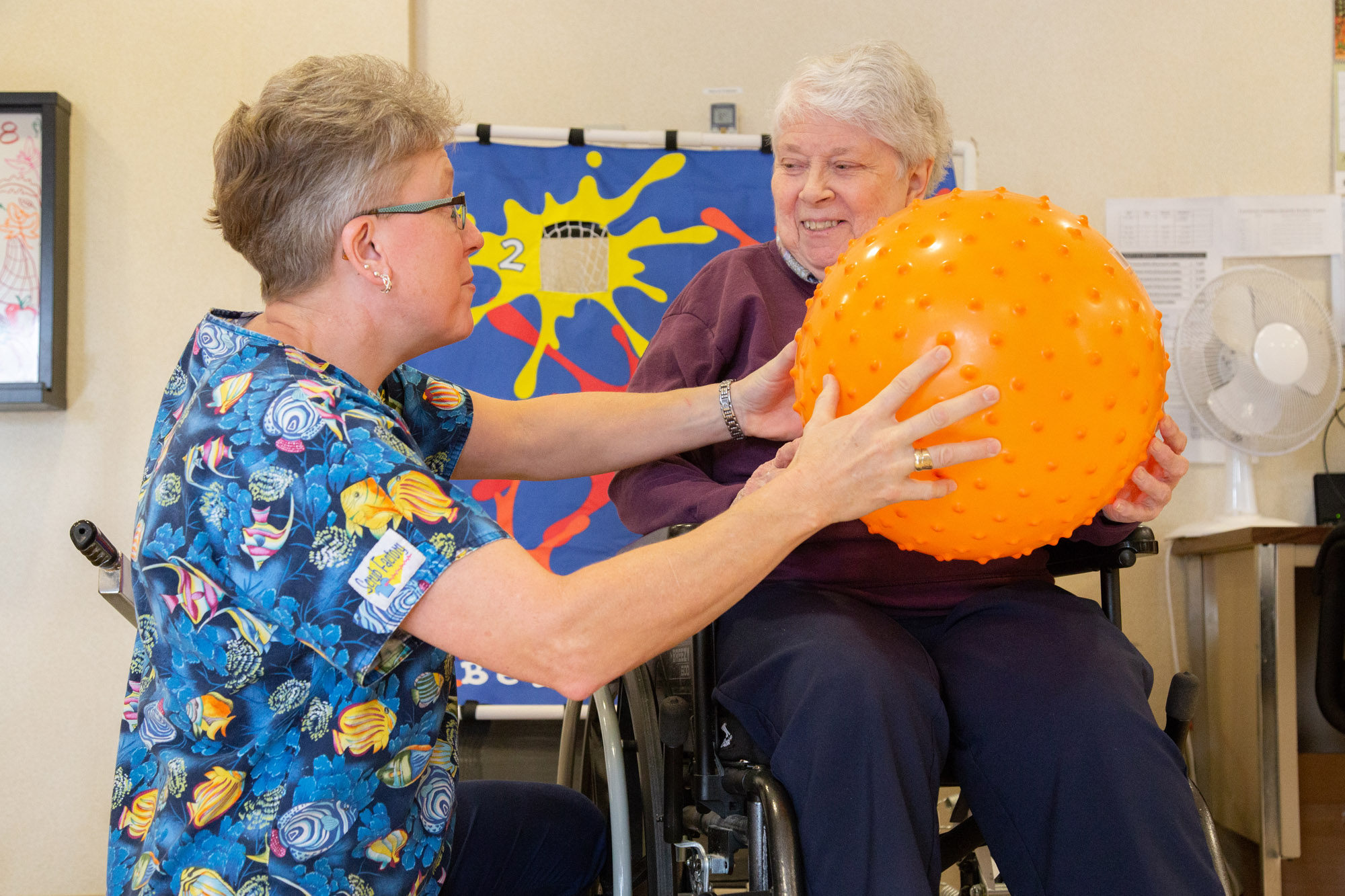 Staff assisting a resident with a therapy ball