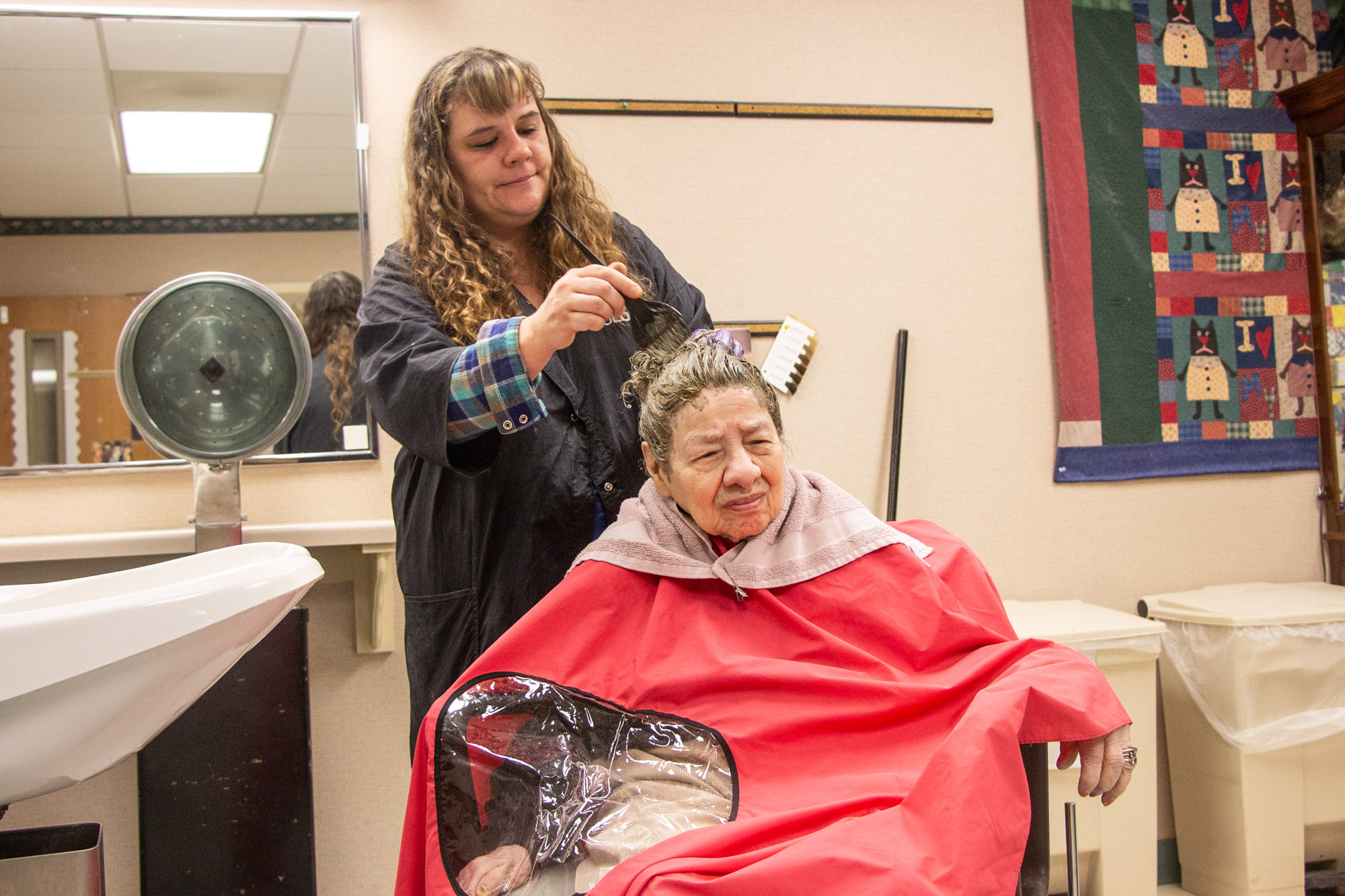 A resident receiving hair care from staff in a salon area
