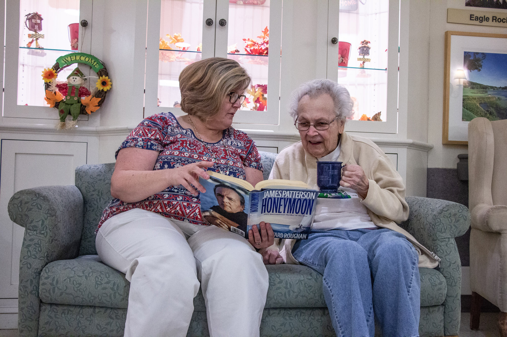 Staff member reading with a resident in a cozy living area