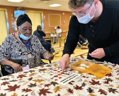Resident and staff engaged in an activity at a table
