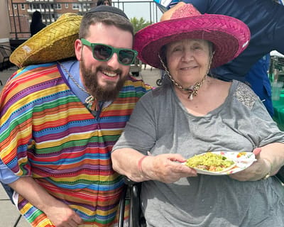 A resident enjoying food with staff during a celebration