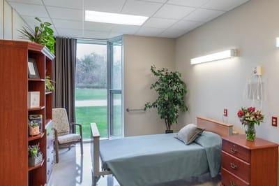 Bright interior of a resident room with a bed and plants