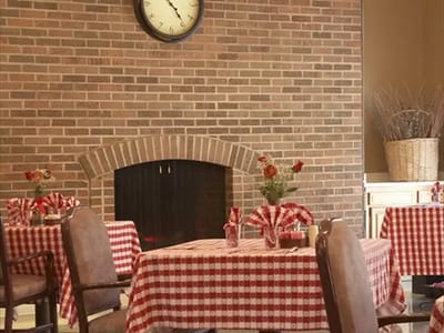 Dining area with checkered tables and a brick fireplace