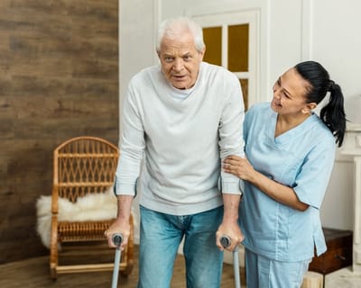 Avamere Rehabilitation of Clackamas, nursing home in Gladstone, OR — Senior man using crutches with caregiver assistance