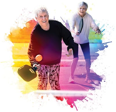 Two senior women playing pickleball outdoors