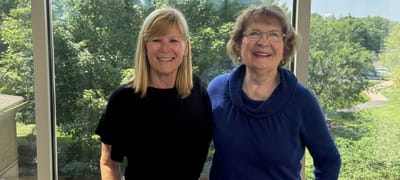 Two women smiling together in a sunny interior space