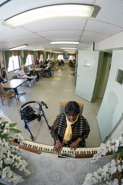 A resident playing piano in an activity room
